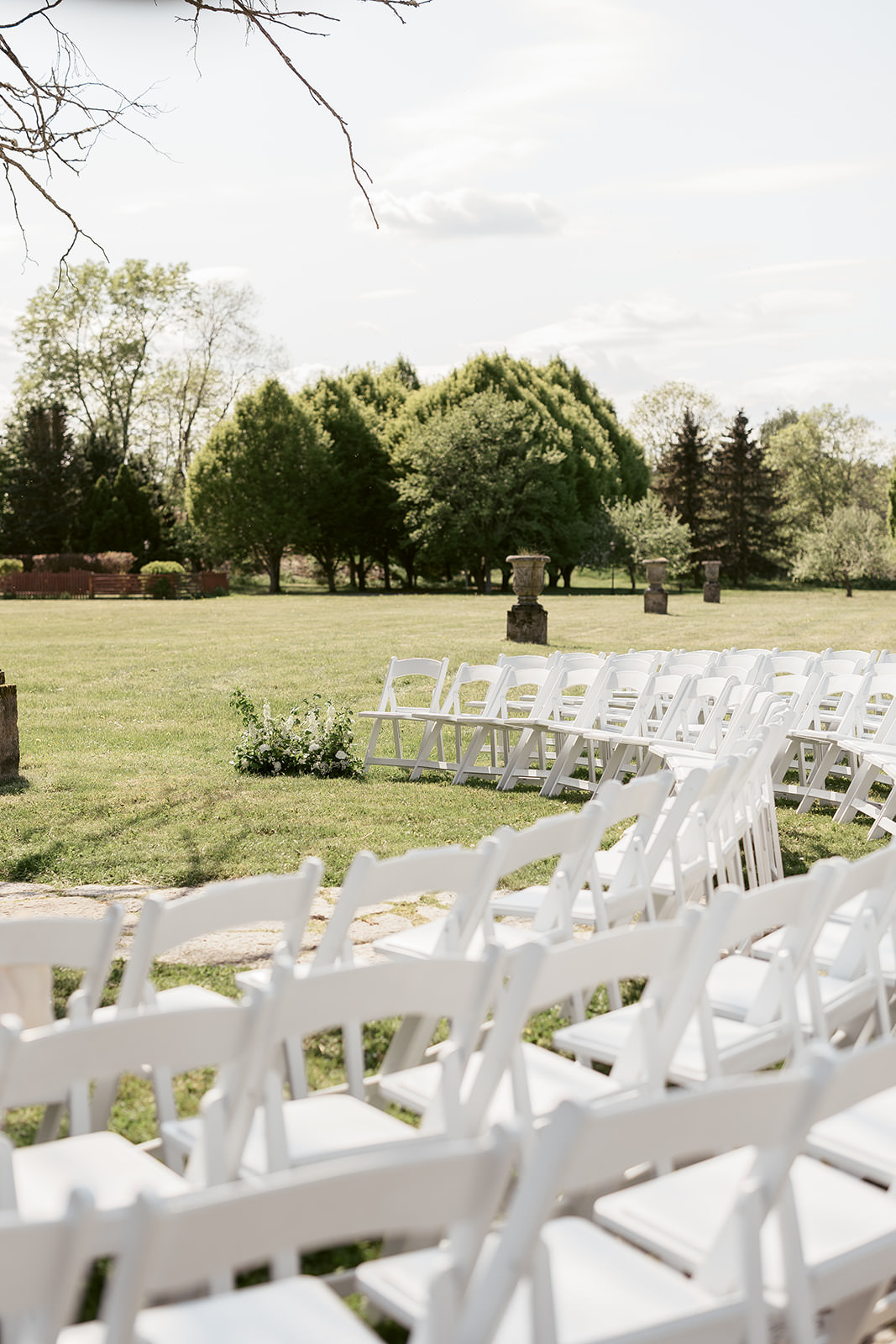 Photo of a spring wedding ceremony setup at Häringe Slott in Stockholm. White chairs are arranged in an arc under the sunny sky. Captured by wedding photographer Karin Lundin. Planned by Right Style Wedding.