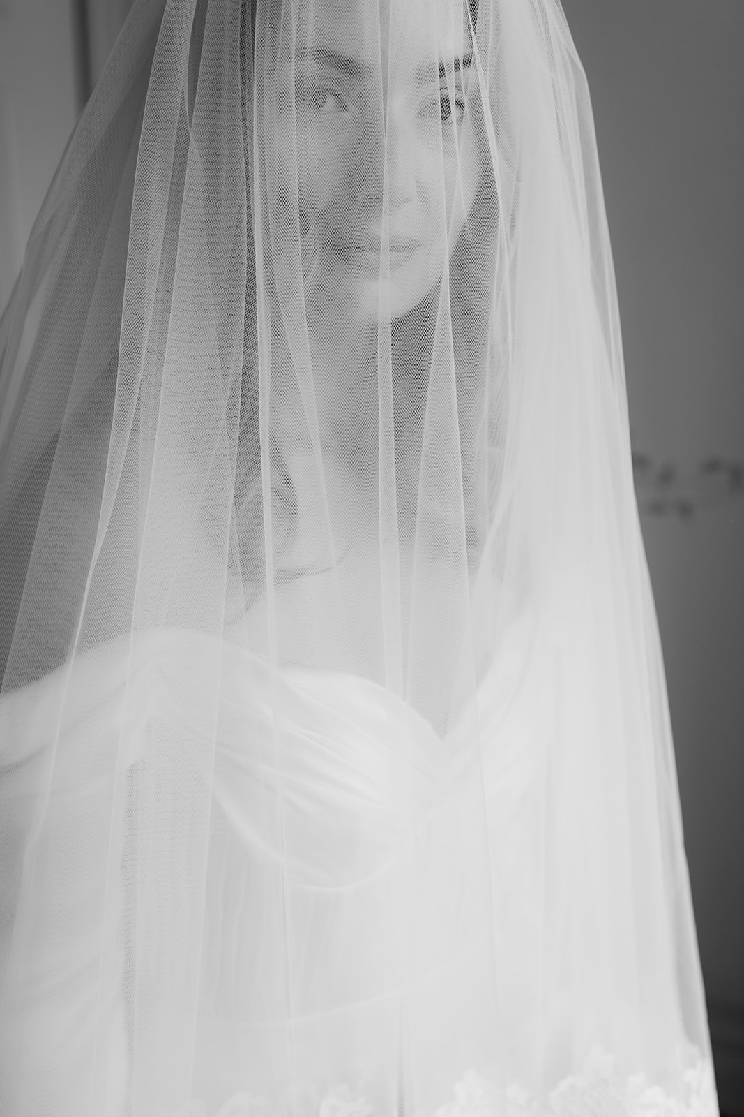 Black and white portrait of a bride on her wedding day at Jordberga Herrgård. Captured by wedding photographer Karin Lundin. Her veil softly covers her face as she looks calmly into the camera. Planned by Freddy Wedding.