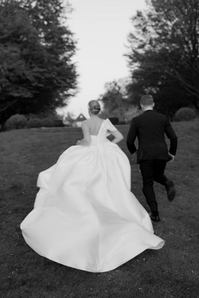 Wedding at Norrvikens trädgårdar 68 Black and white: the bride and groom run into the park, seen from behind