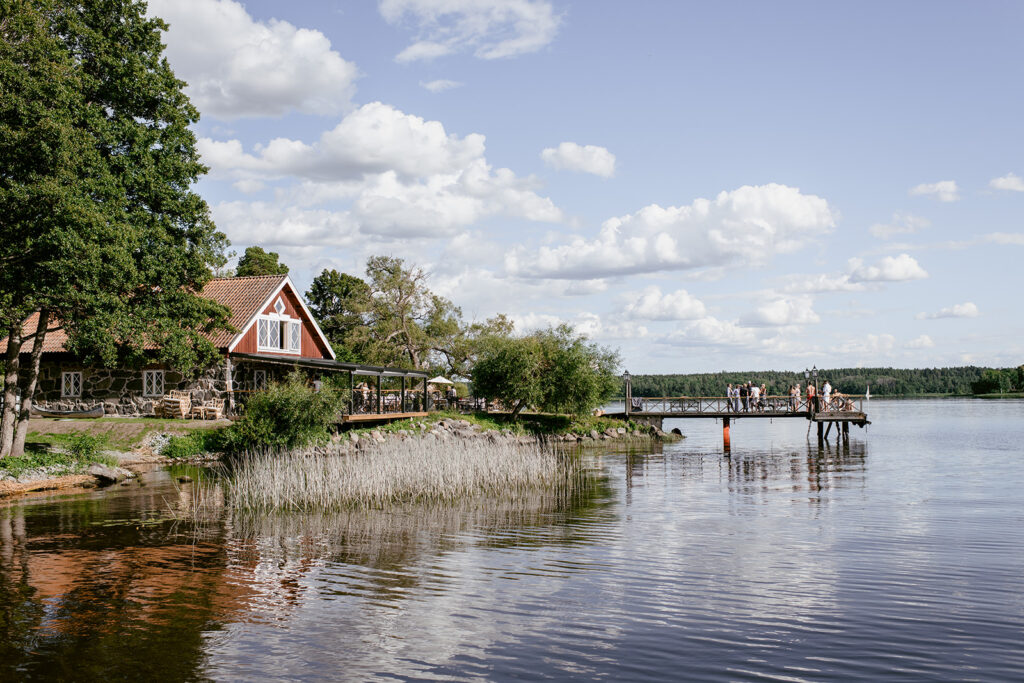 Slottsbröllop i Sverige: slott och herrgårdar 11 Krusenberg Herrgård sedd från sjön med rött sjöbodstak och spegelblank vattenyta