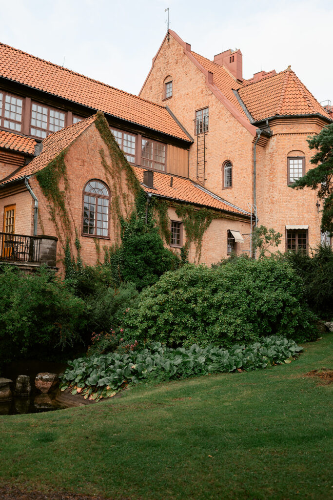 Exterior of Högberga Gård, the traditional red wooden building surrounded by greenery on Lidingö