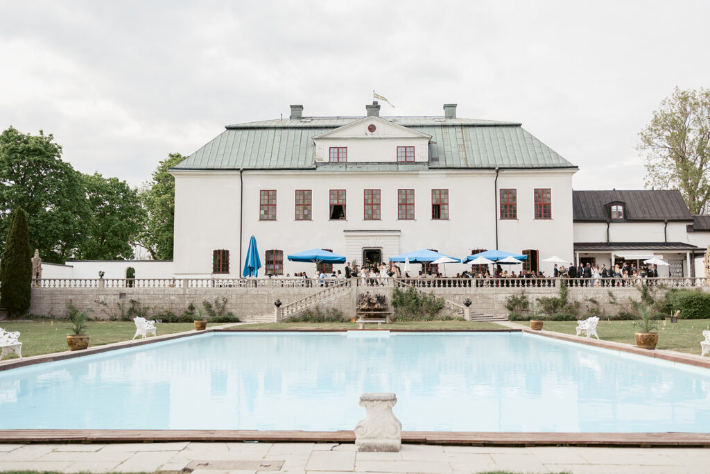 Häringe Slotts huvudbyggnad med pool och parasoll i förgrunden