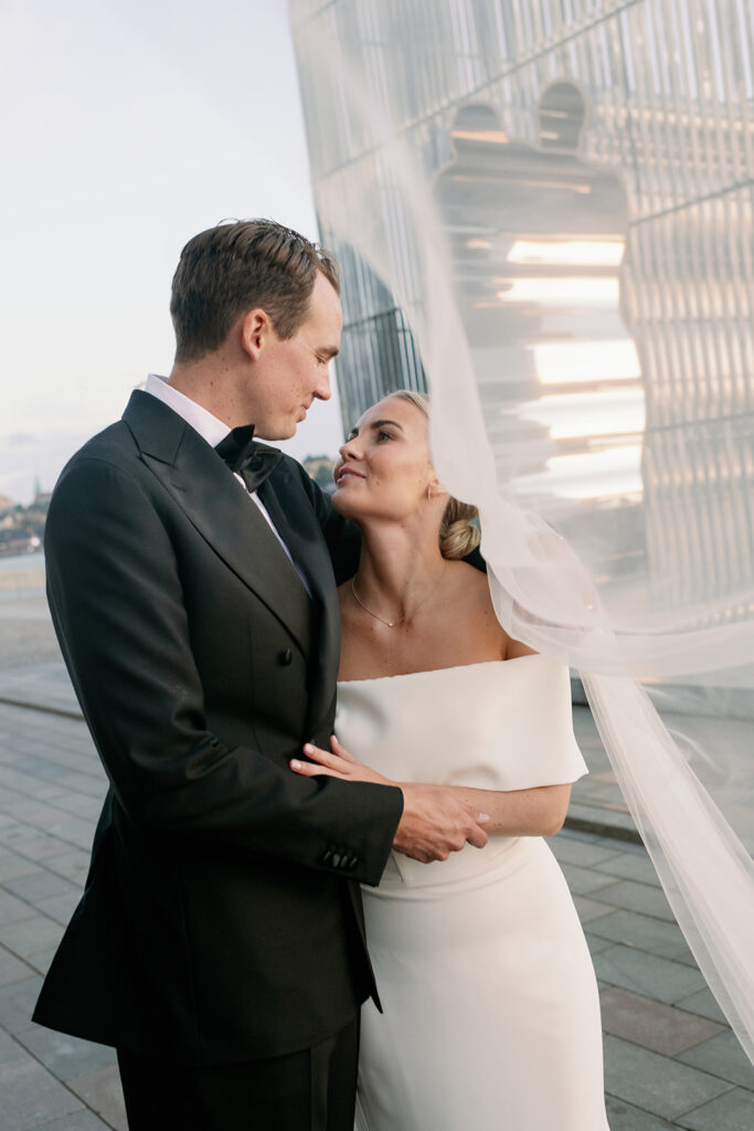 Bride's veil in the wind around the groom in a dinner jacket, black tie wedding in Stockholm