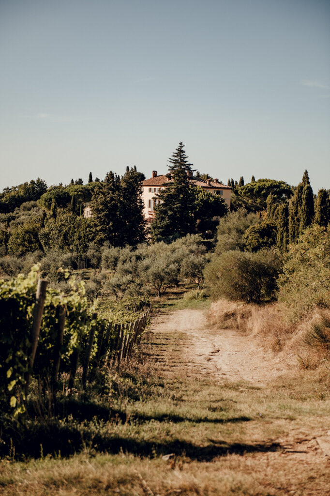 Groom adjusting tie in front of Tuscan villa, candid portrait