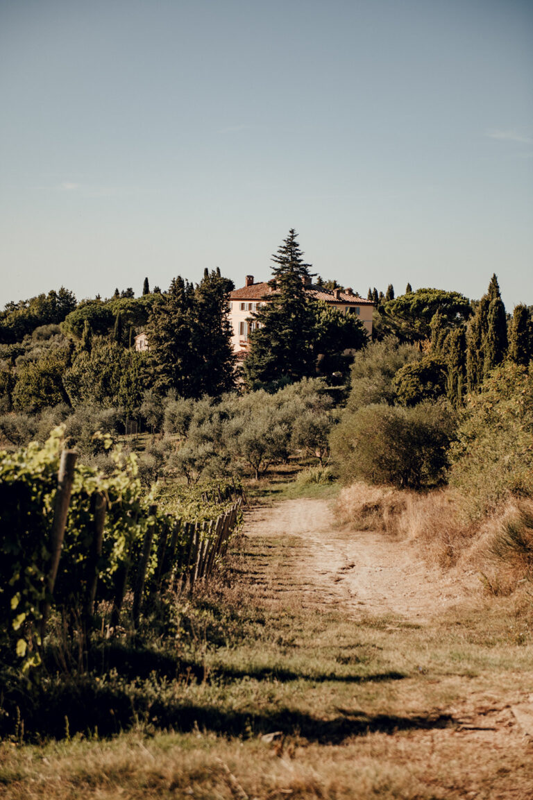 Groom adjusting tie in front of Tuscan villa, candid portrait