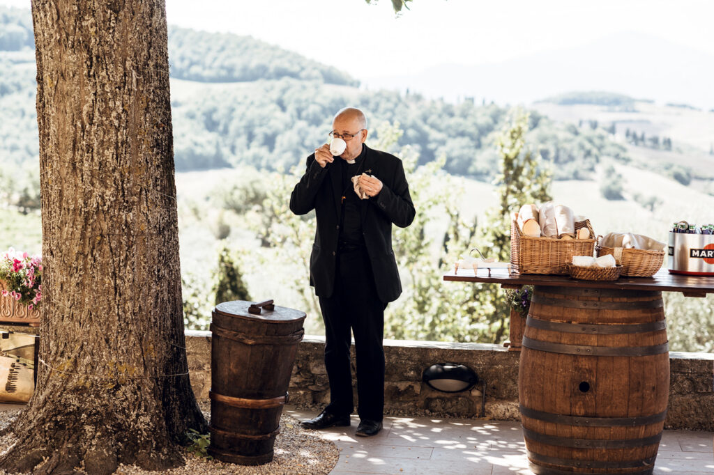 Groom pouring drinks at outdoor bar with wine barrels, Tuscany