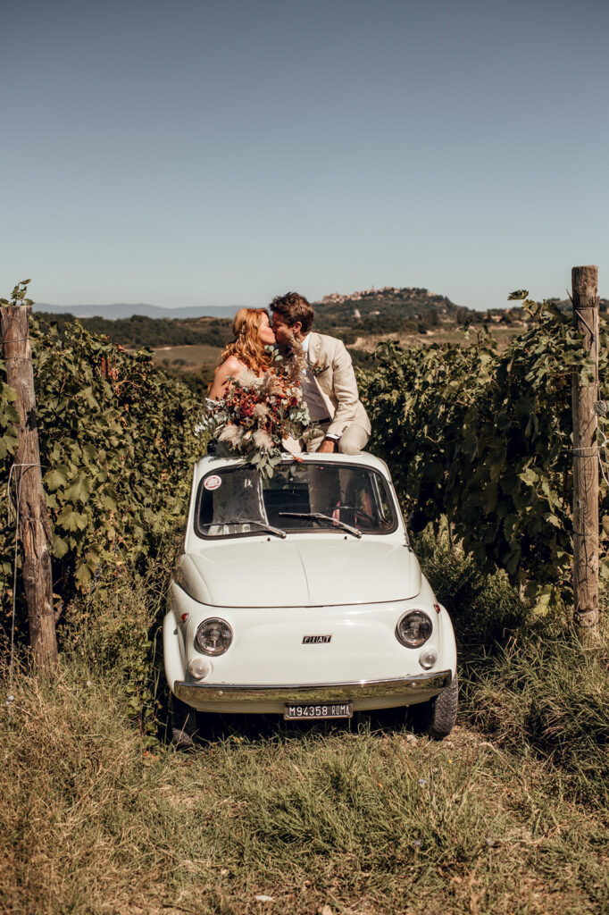 Bride and groom with vintage Fiat 500 on Tuscan hillside