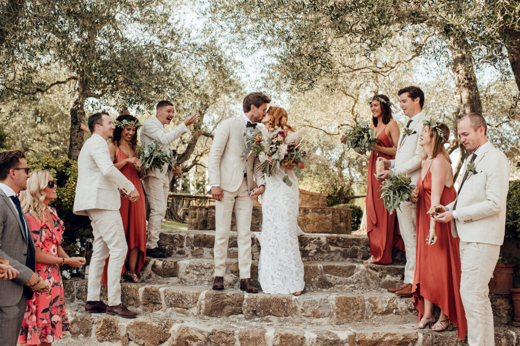 Bride and groom with wedding party on stone steps, Tuscan villa