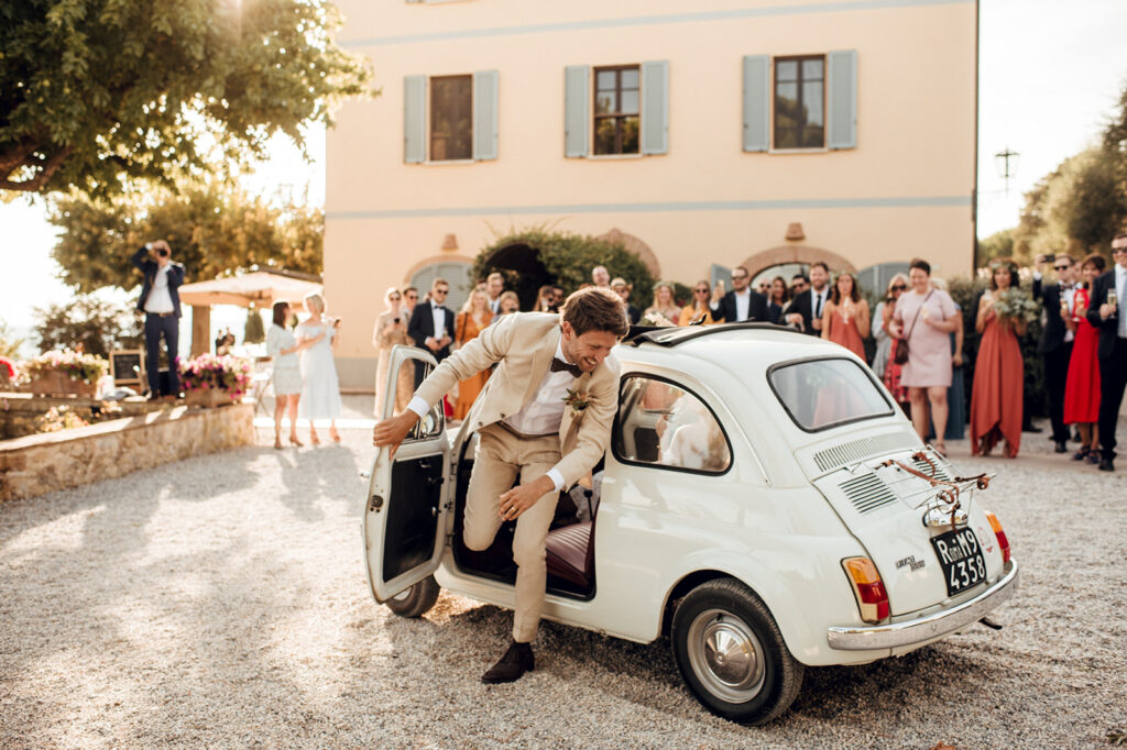 Bride and groom in vintage Fiat 500 at Italian villa courtyard