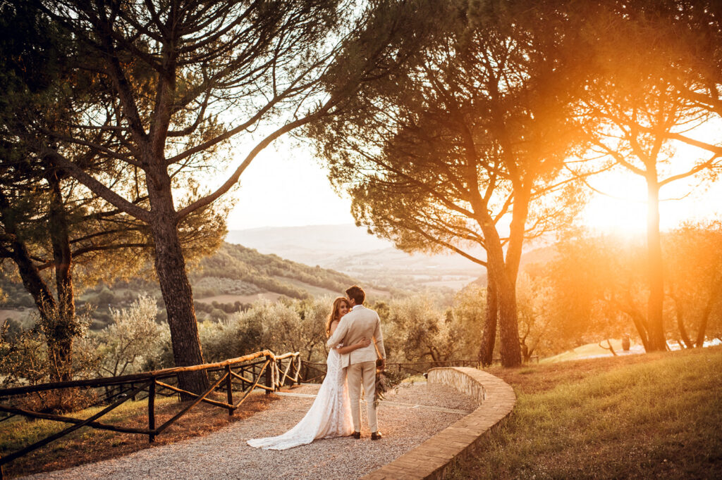 Bride and groom at sunset under tree with Tuscan hills, Italy