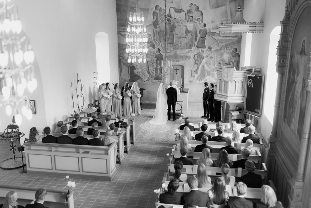 Vigselceremoni inne i Torekovs kyrka med gäster i bänkarna, svartvitt