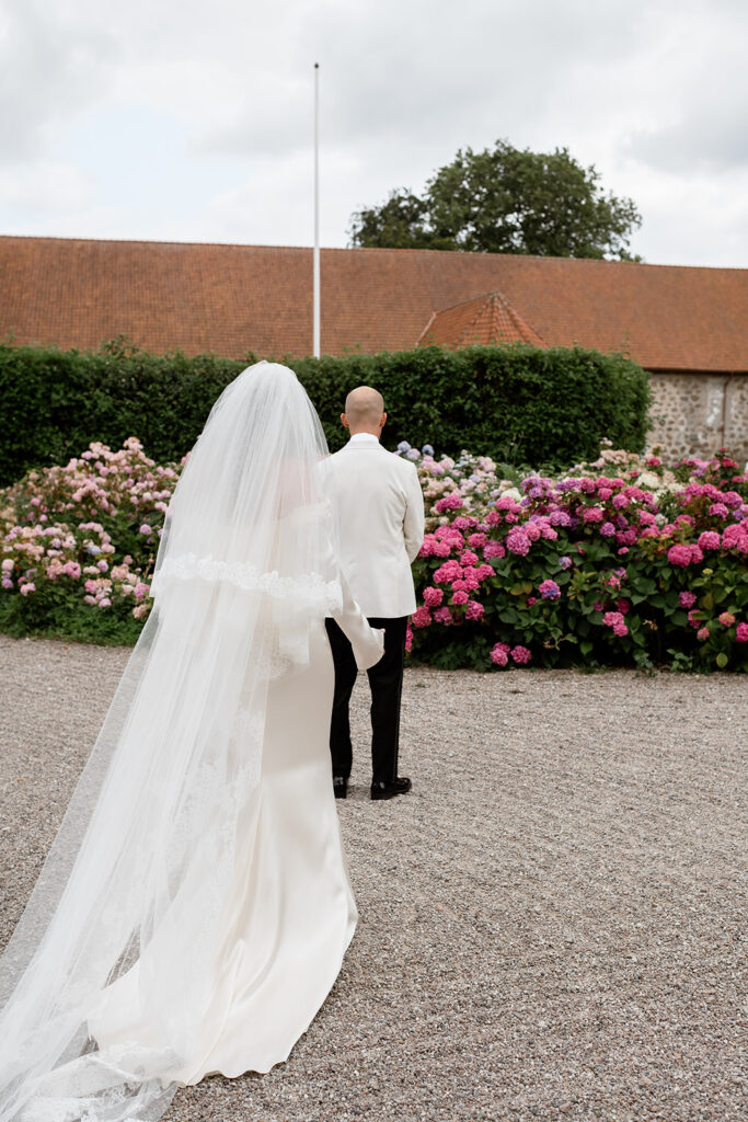Wedding at Jordberga: a photographer's guide 5 Bride in a long veil beside rhododendrons in the park