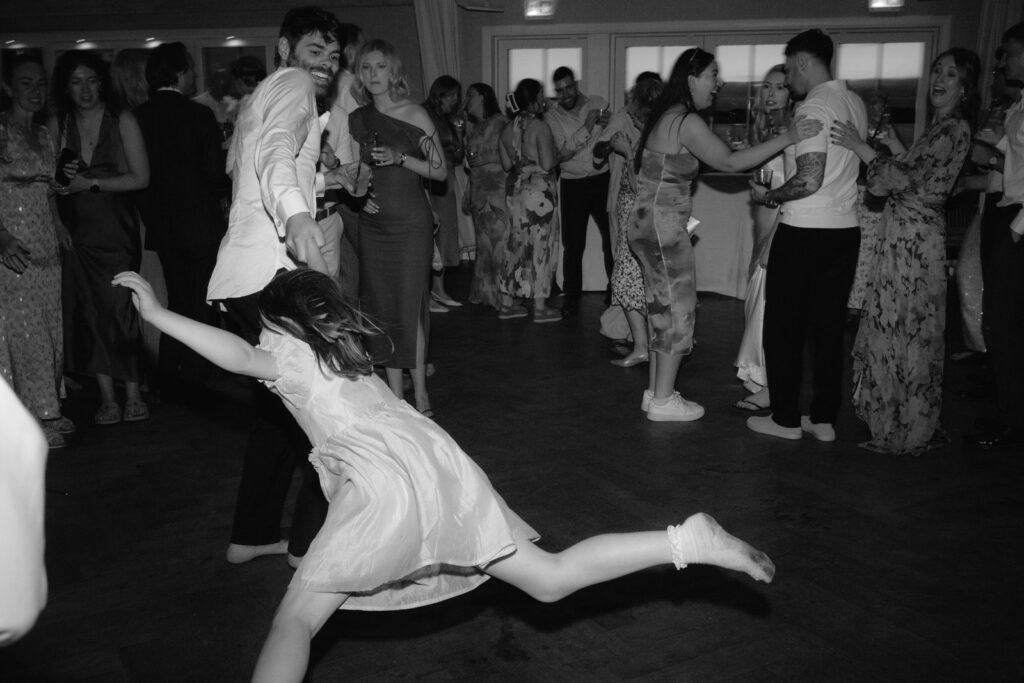 Brudpar och gäster dansar på dansgolvet, dokumentärt bröllopsfoto i svartvitt