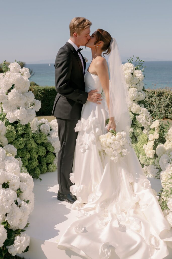 Bride and groom holding hands beside a floral arrangement