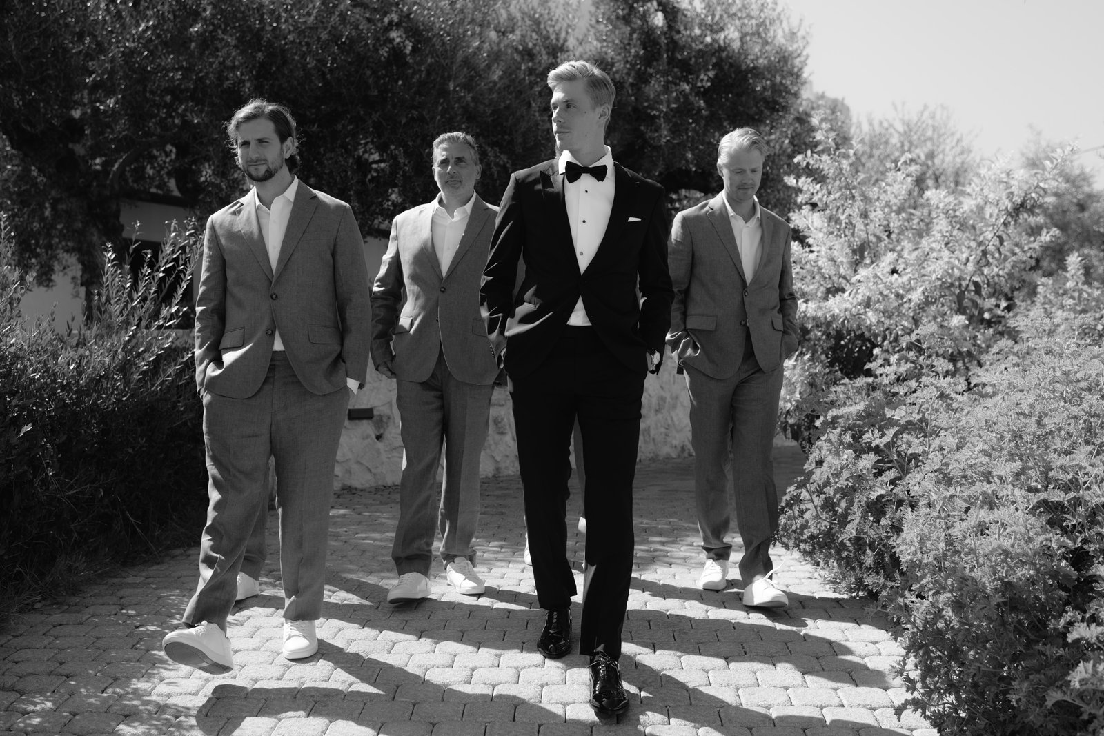 Black and white photograph of the groom and groomsmen walking outdoors