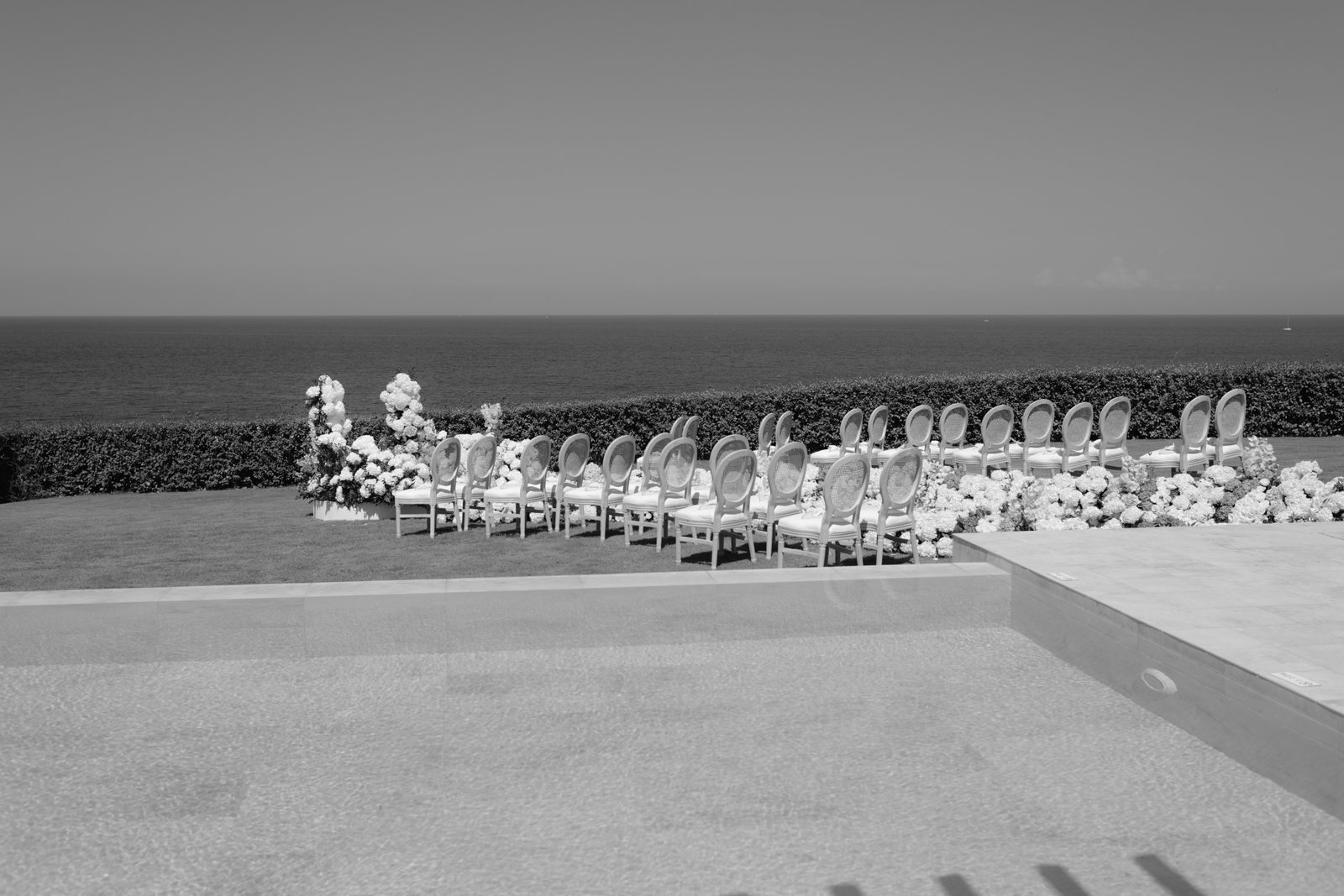 Chairs set out for a ceremony by the sea, black and white