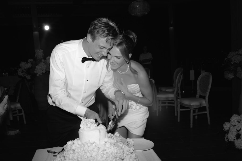 Fine art wedding photographer Sweden, black and white photograph of a couple cutting their wedding cake by candlelight