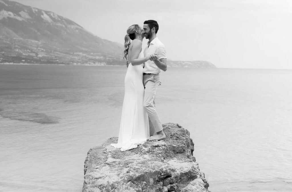 Wedding couple kissing on a rock in the sea on Kefalonia, black and white