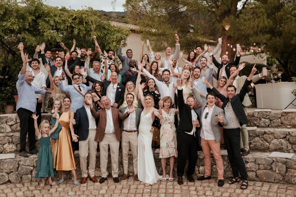 Wedding guests cheering with arms in the air on the steps at Millstone Villa, Kefalonia