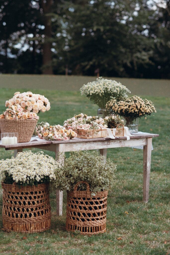 Wooden table with flowers in baskets and pots on the lawn, shot on 35mm film