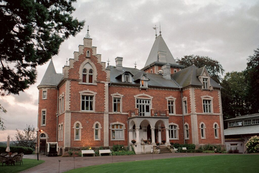 Wedding at Thorskogs Slott 35 Thorskogs Slott in red brick with its turret, seen across the lawn in evening light, shot on 35mm film