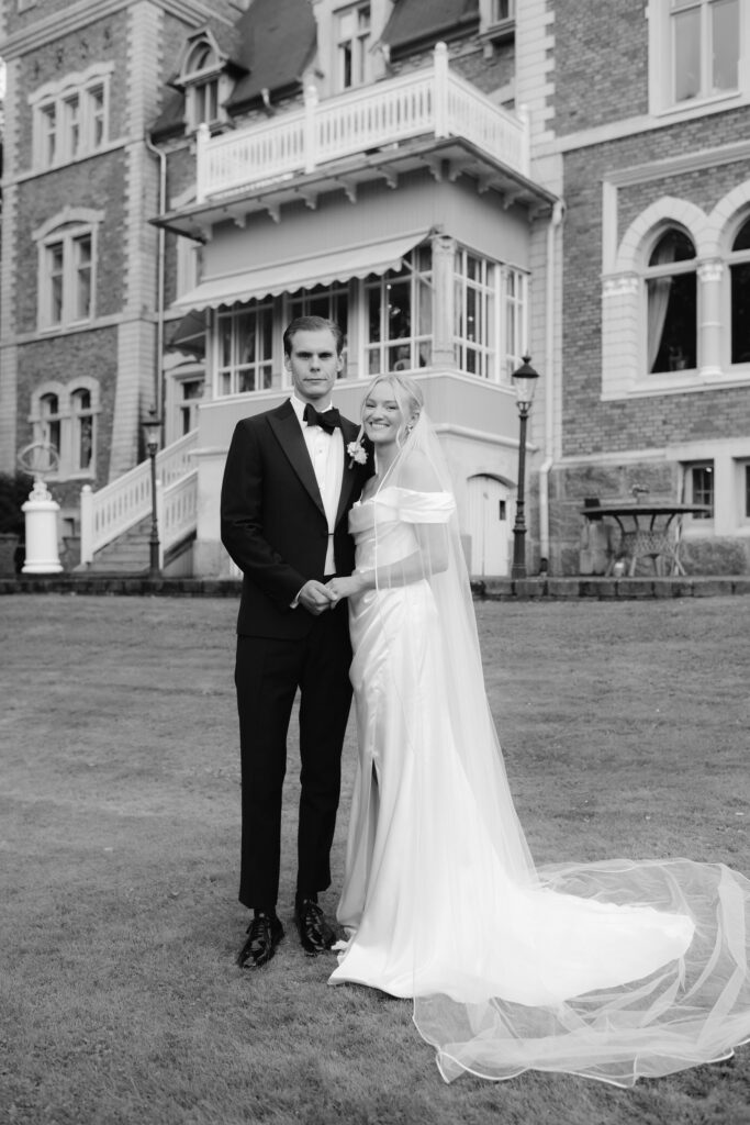 Wedding at Thorskogs Slott 12 Black and white: the couple stands in front of the castle with the terrace and steps behind