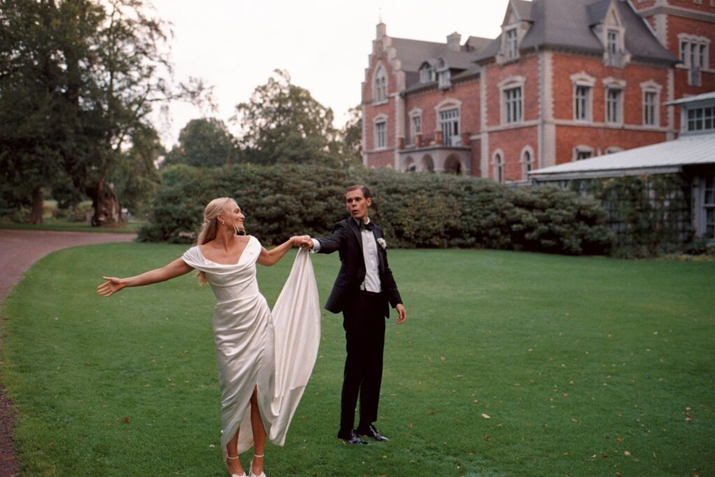 Wedding at Thorskogs Slott 33 The couple holds hands and dances on the lawn in front of the castle, shot on 35mm film