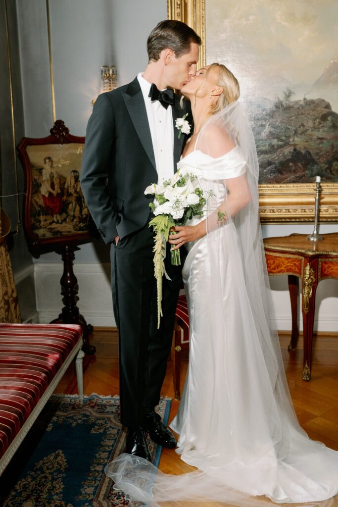 Wedding at Thorskogs Slott 24 The couple kisses in a salon with old paintings and antique furniture