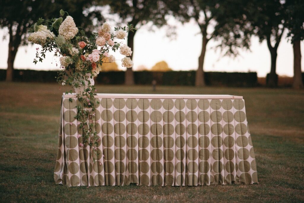 Ceremony table draped in patterned fabric with flowers, the park behind in evening light, shot on 35mm film