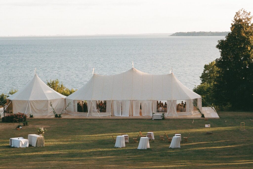The marquees on the lawn above the Öresund strait with white standing tables in front, shot on 35mm film