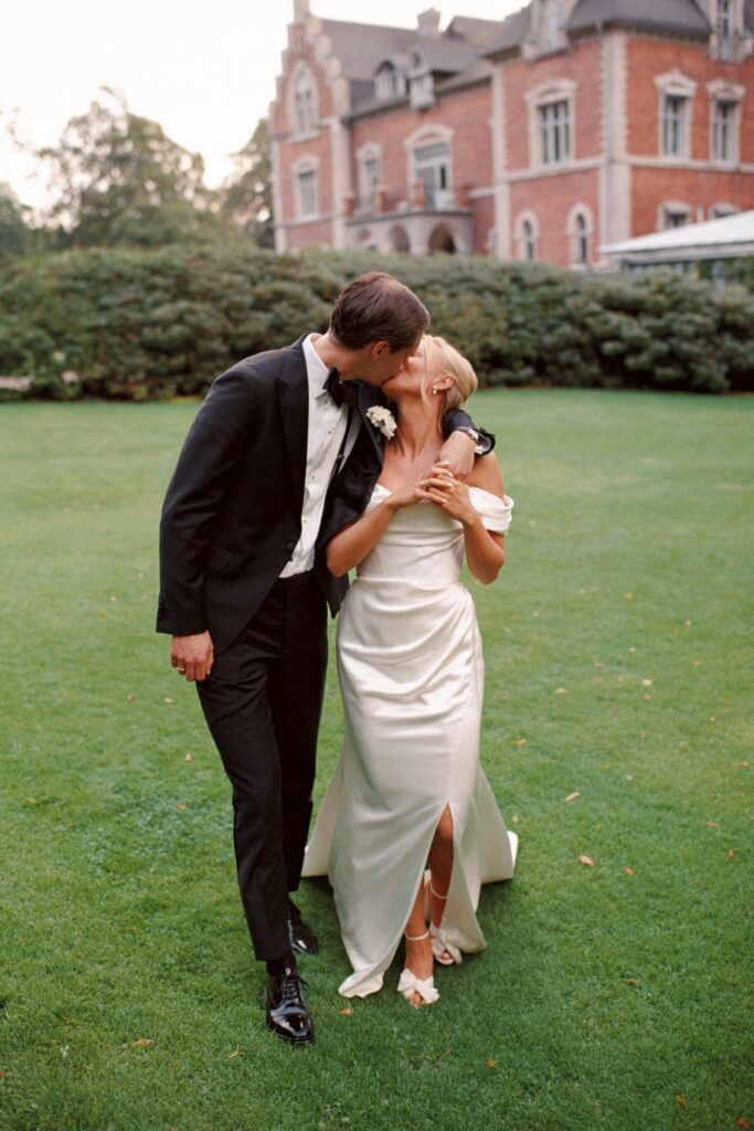Wedding at Thorskogs Slott 32 The couple kisses on the lawn with the castle in the background, shot on 35mm film
