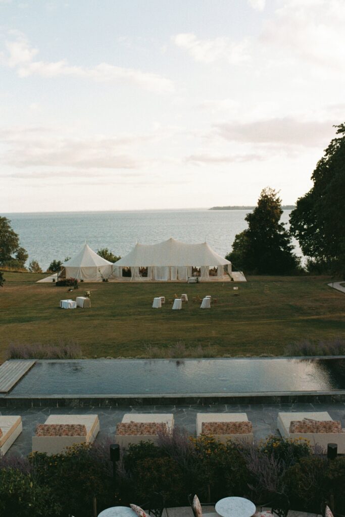 Marquees on the lawn with the Öresund strait behind and a long narrow pool in the foreground, shot on 35mm film