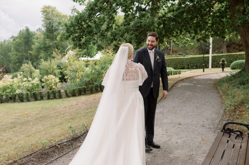 Bröllop på Villa Fridhem: en fotografs guide 13 Brudgummen vänder sig om och ser bruden på grusgången i parken