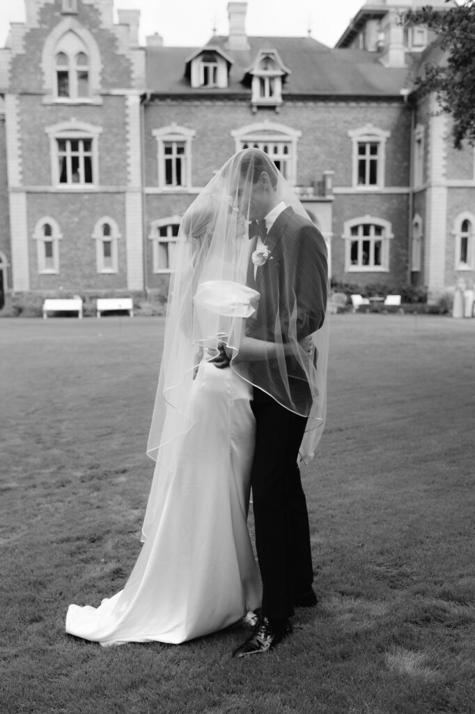 Wedding at Thorskogs Slott 20 Black and white: the couple under the veil in front of the brick facade of the castle