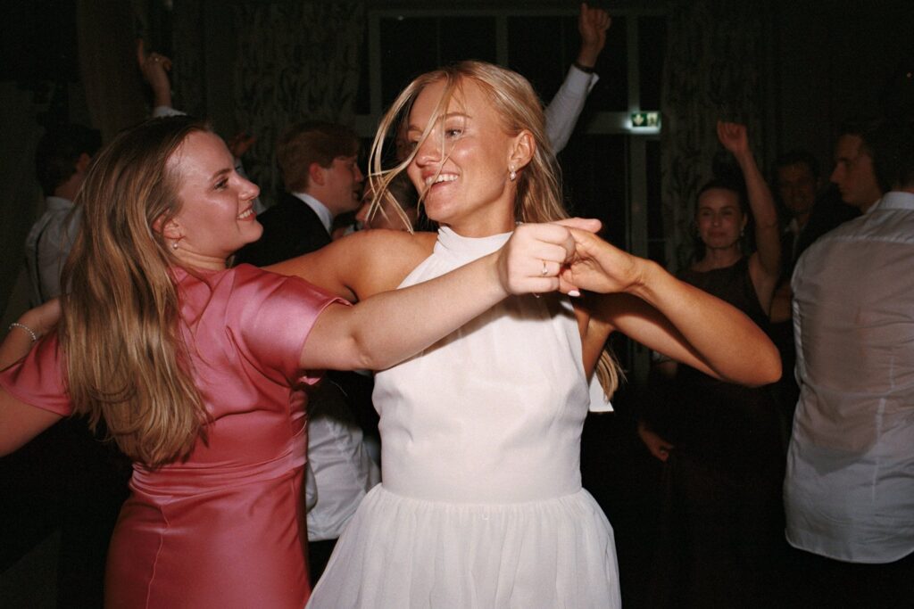 Wedding at Thorskogs Slott 19 The bride dances with a friend in a pink dress at the party, shot on 35mm film