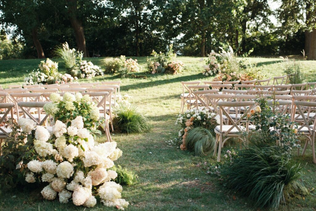 Rows of chairs on the lawn with a large white hydrangea arrangement in the foreground, shot on 35mm film