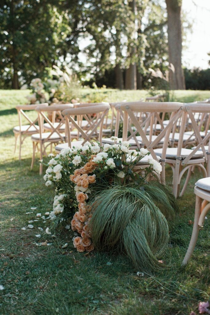 Wooden chairs along the aisle with a floral arrangement in peach and white, shot on 35mm film