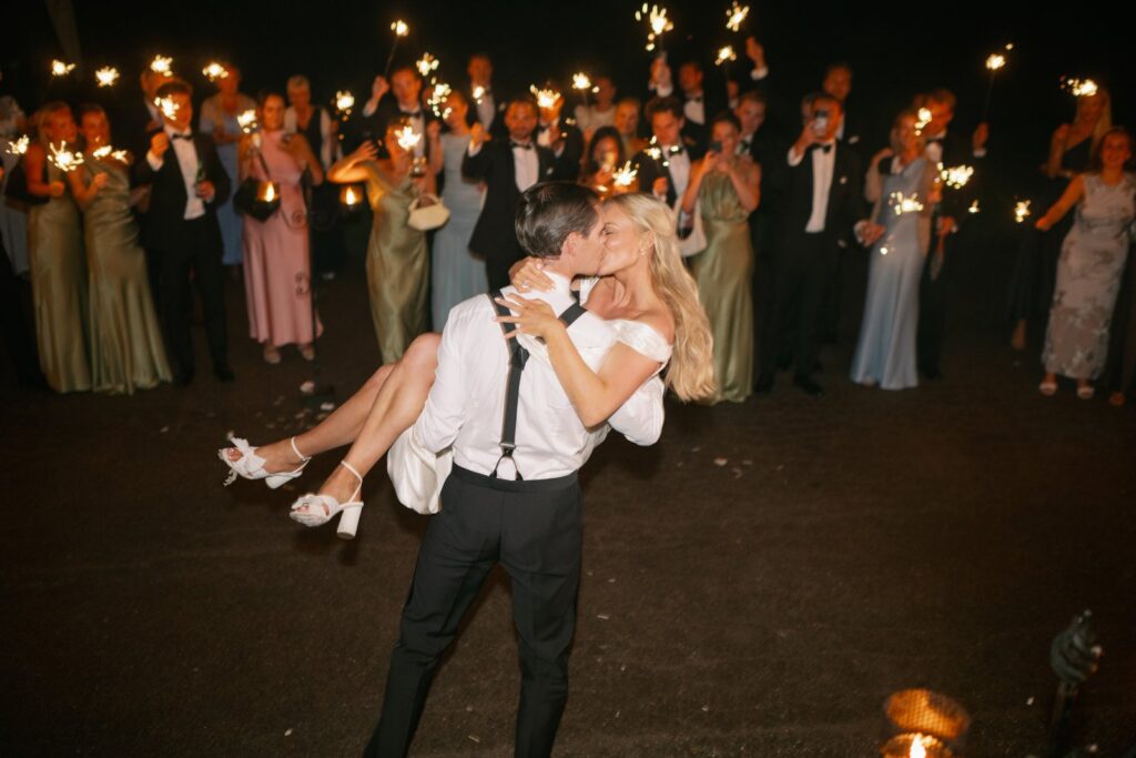 Wedding at Thorskogs Slott 22 Guests hold sparklers as the groom lifts the bride in the dark