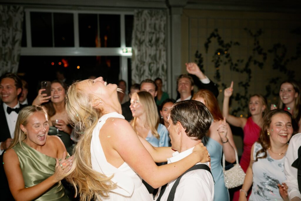 Wedding at Thorskogs Slott 23 The bride laughs with her head thrown back among guests on the dance floor