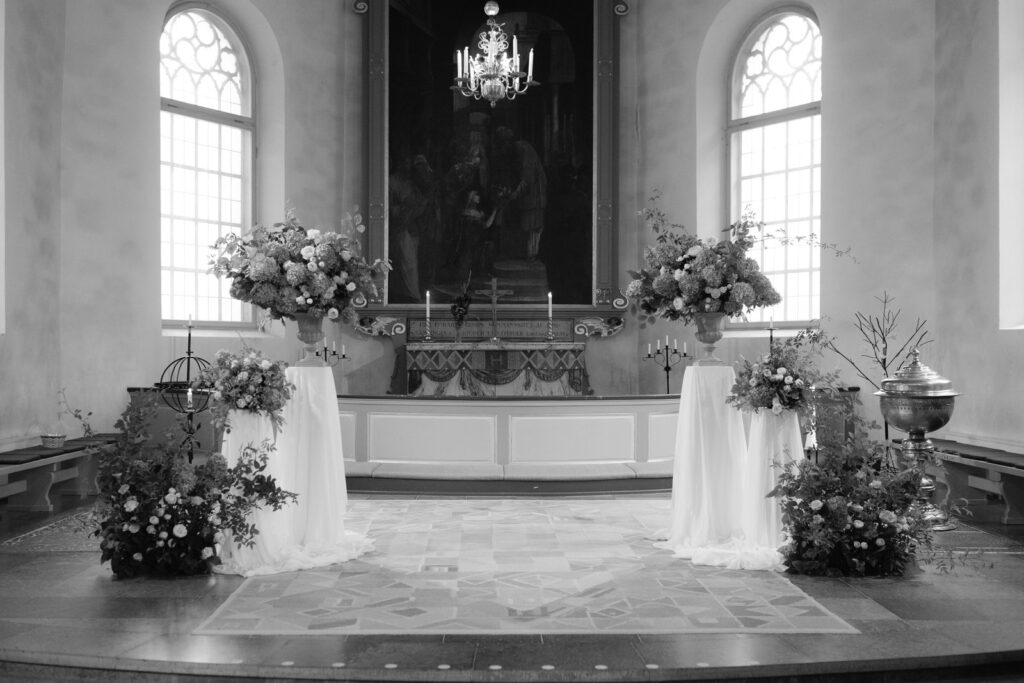 Black and white: a church altar with floral arrangements on pedestals and a chandelier