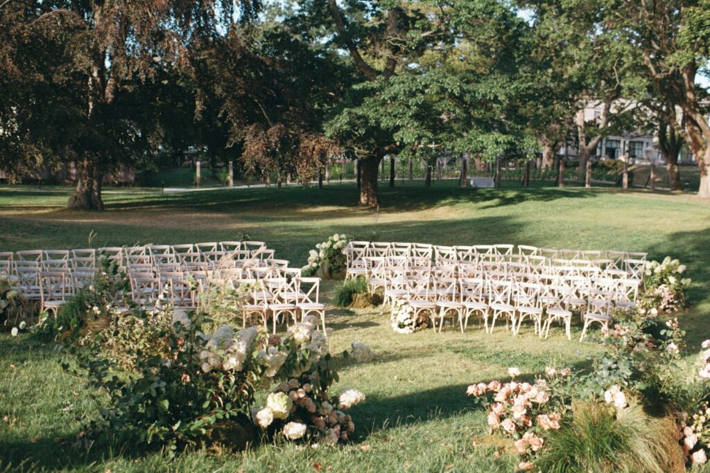 The ceremony set up on the lawn in the park, curved rows of chairs and low floral arrangements, shot on 35mm film