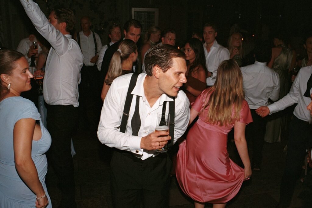 Wedding at Thorskogs Slott 34 A guest in braces dancing among the crowd with arms in the air, shot on 35mm film