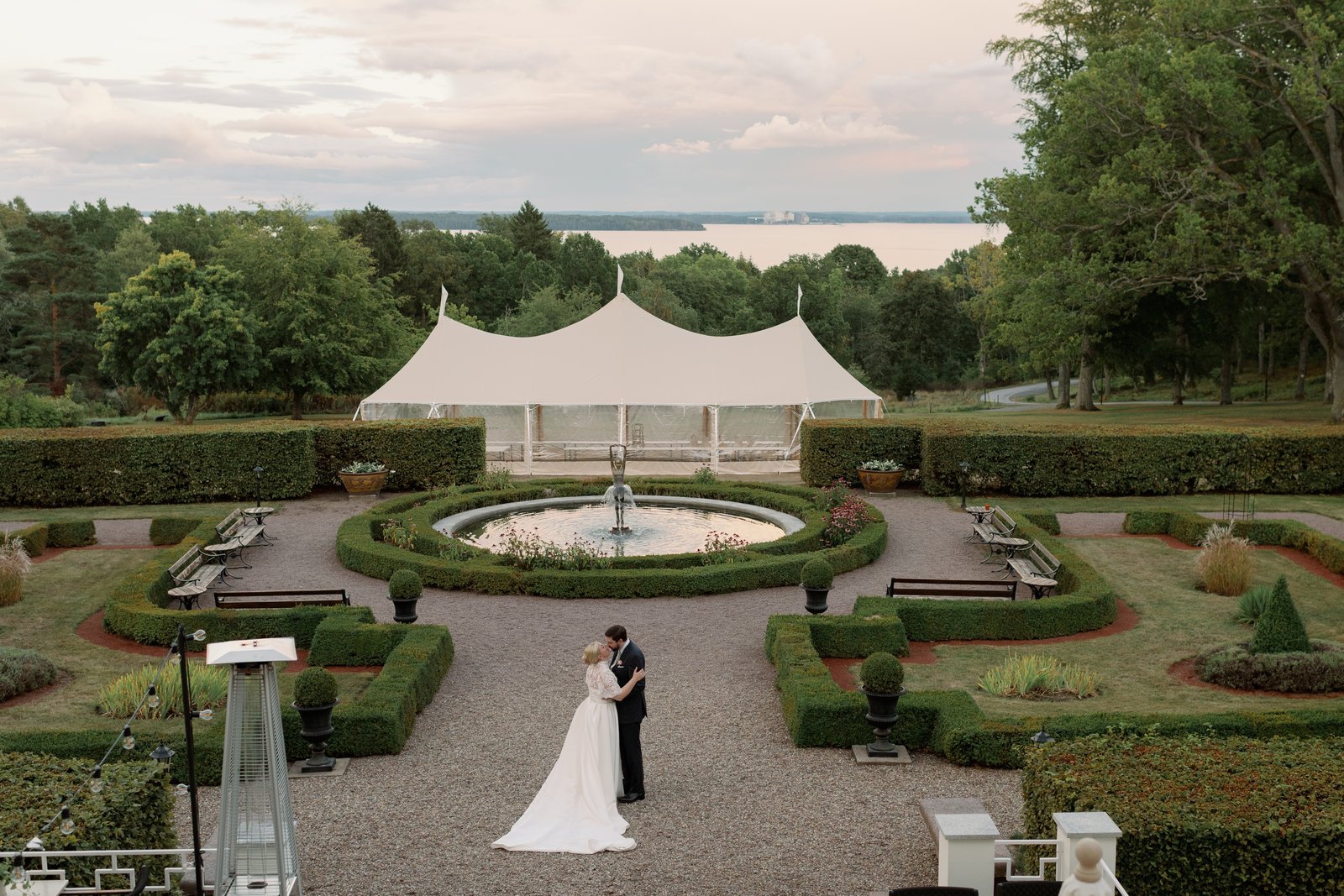 Bröllop på Villa Fridhem: en fotografs guide 3 Brudparet i den formella trädgården med fontänen och Bråviken bakom