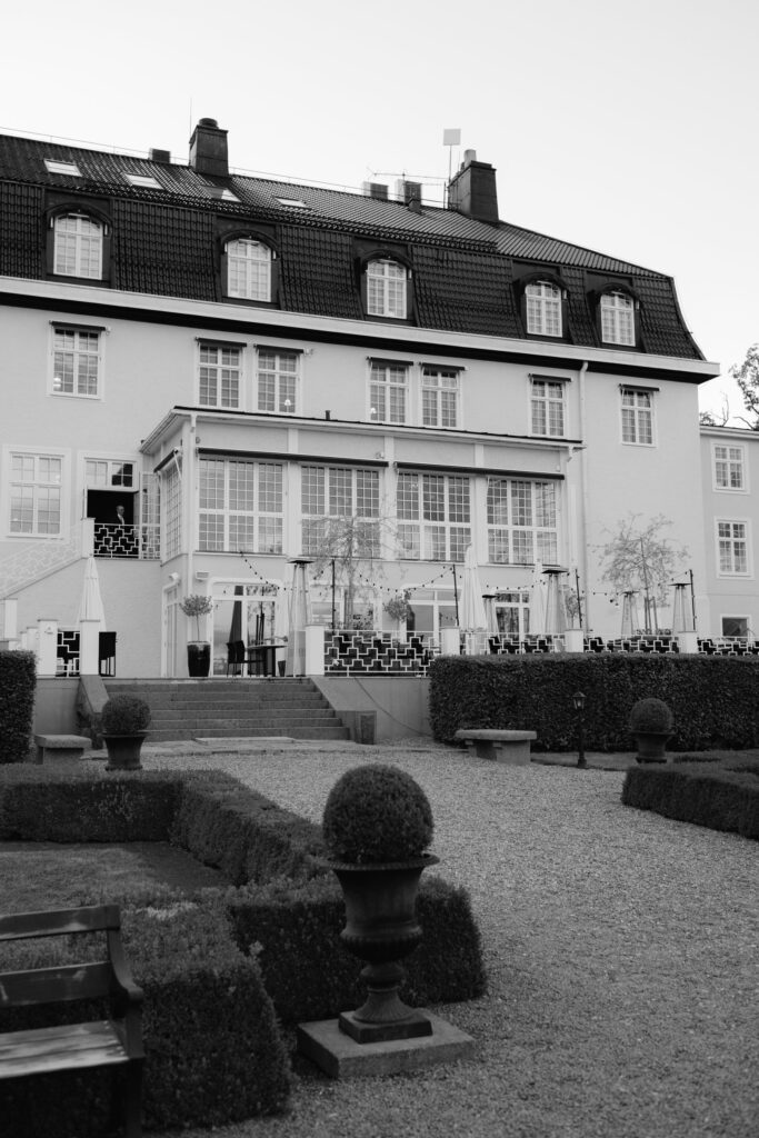 Bröllop på Villa Fridhem: en fotografs guide 9 Svartvitt: villans fasad med glasveranda ovanför den klippta trädgården