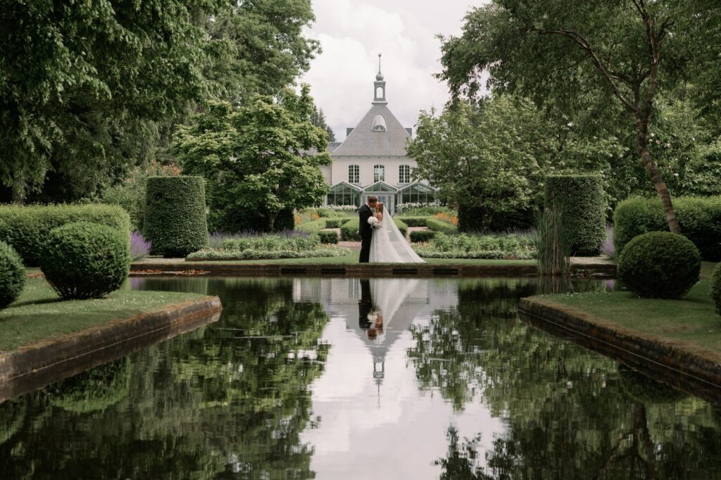 Wedding at Norrvikens trädgårdar 35 Wedding at Norrvikens trädgårdar: the couple reflected in the pond in front of Villa Abelin, clipped box hedges around the water