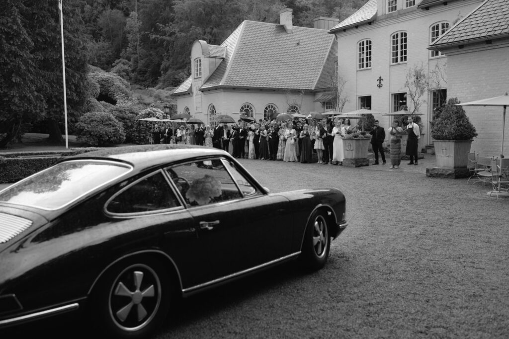 Wedding at Norrvikens trädgårdar 27 Black and white: the vintage car on the forecourt of a white villa where guests have gathered