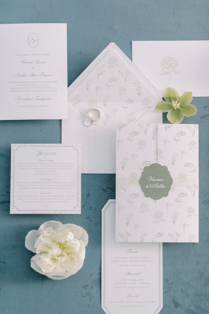 Wedding at Norrvikens trädgårdar 22 Wedding stationery with invitation and menu on blue velvet, a white flower and a green orchid