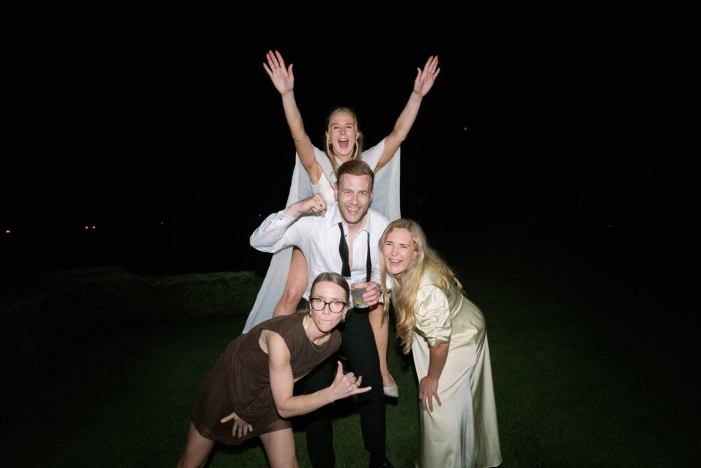 Wedding at Norrvikens trädgårdar 21 The bride and three guests pulling playful faces in the dark, lit by flash
