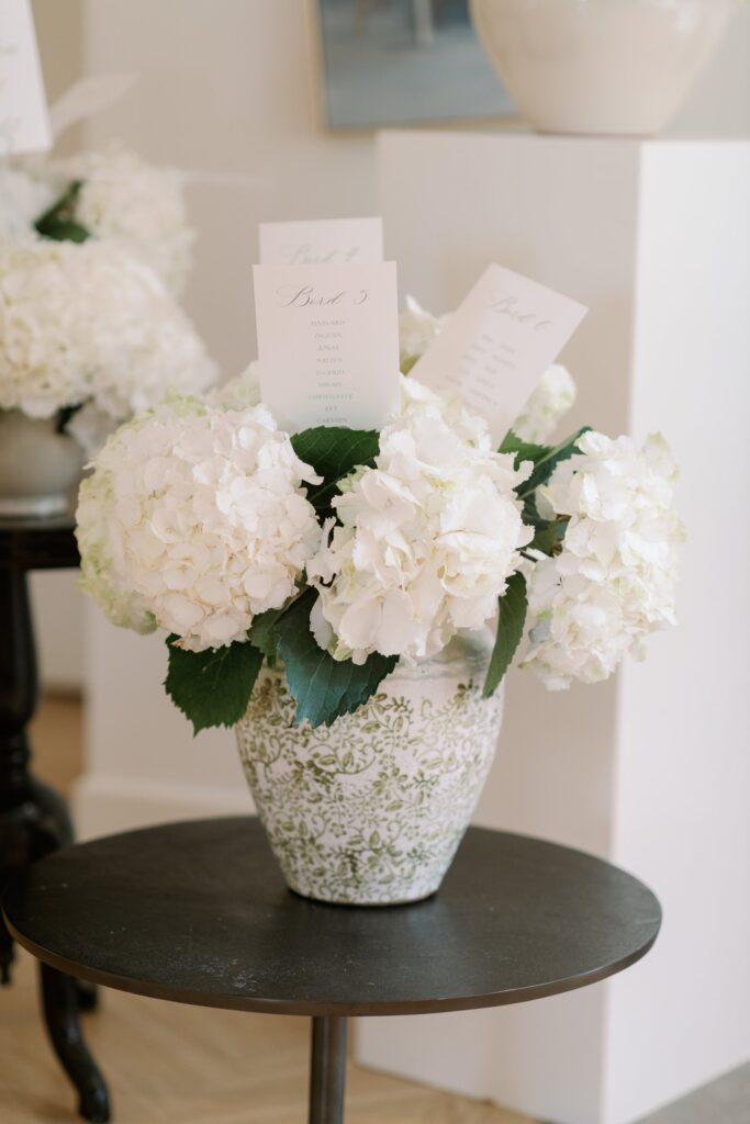 Wedding at Norrvikens trädgårdar 16 White hydrangeas in a vase with seating cards on a round table