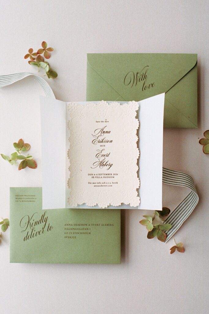 Wedding invitation with green envelopes and leaves on a white background, shot on 35mm film